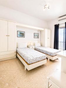 two beds in a room with white walls at The Horizon - Sea View 8 in Sliema