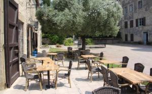 an outdoor patio with tables and chairs and a tree at Les Chambres Cast'elles in Malves +8 photos