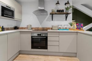 a kitchen with white cabinets and a stove top oven at The Courtyard in Exeter +7 photos