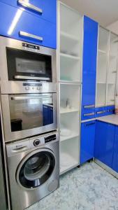 a kitchen with a washing machine and blue cabinets at El balcón de Mafalda in Villarcayo