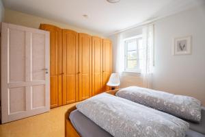two beds in a bedroom with wooden cabinets and a window at Ferienwohnung Gartengeschoss in Durbach