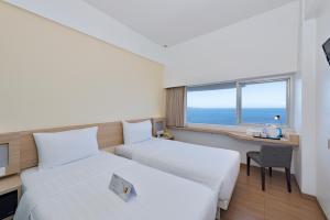 a hotel room with two beds and a desk and a window at Whiz Prime Hotel Megamas Manado in Manado +17 photos