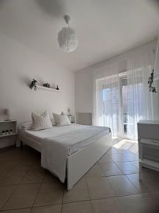 a white bedroom with a large bed and a window at TERRACINA Central Rooms in Terracina