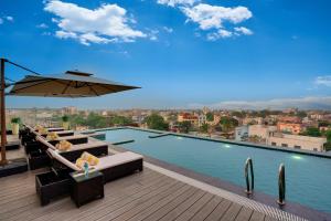 a swimming pool with a table and an umbrella at Lemon Tree Premier, Biratnagar, Nepal in Biratnagar