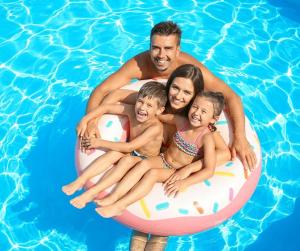 Ein Mann und zwei Kinder sitzen auf einem Floß in einem Pool in der Unterkunft Villa Clariss in Balatonalmádi