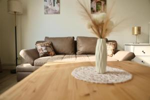 a living room with a couch and a vase on a table at Olive Residence Lübeck in Lübeck