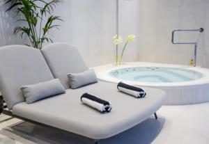 a bath tub sitting next to a white chair with two pillows at Dwór Prezydencki Boutique Hotel & SPA in Tarnów
