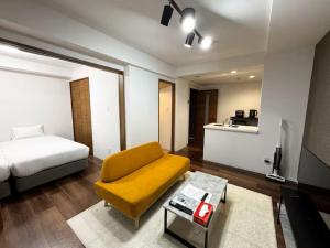 ein Wohnzimmer mit einem Bett und einer gelben Couch in der Unterkunft ハミルトンイースト in Sapporo