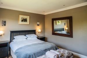 a bedroom with a large bed and a mirror at Shores Keep - Self Catering Home in Hermanus