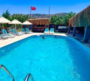 a large blue swimming pool with chairs and a red flag at Fesleğenbükü Kamp in Çökertme