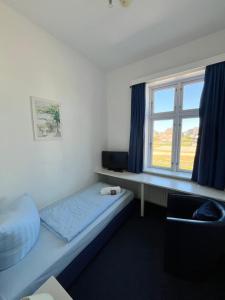 a small bedroom with a bed and a window at Strandhotel Sylt Wenningstedt in Wenningstedt