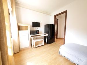 a bedroom with a bed and a desk with a television at Estudio Las Rotas in Denia