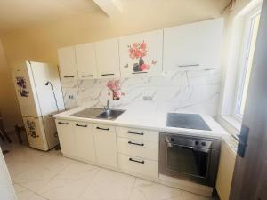 eine Küche mit weißen Schränken, Spüle und Kühlschrank in der Unterkunft Hotel Etrusco in Gherla
