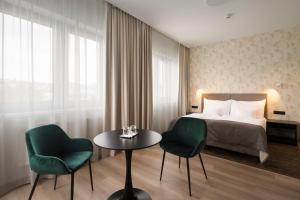 a hotel room with a bed and two chairs and a table at Hotel Tatra in Bratislava