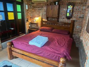 a bedroom with a wooden bed in a brick wall at Lelangit Inn in Port Dickson