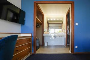 a room with a blue wall with a tv and a hallway at Hotel AMERIQUE in Palavas-les-Flots