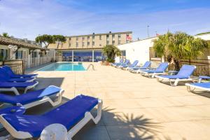 a row of blue lounge chairs next to a swimming pool at Hotel AMERIQUE in Palavas-les-Flots