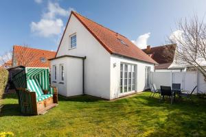 a white house with a yard with chairs and tables at Ant Diekskant in Juist