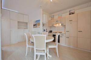 a kitchen with white cabinets and a table and chairs at Bungalow Nebel Nr 3 in Kellenhusen