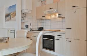 a kitchen with white cabinets and a table and a stove at Bungalow Nebel Nr 3 in Kellenhusen +11 photos