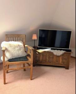 a television sitting on a wooden stand next to a chair at Nicht Daheim und doch Zuhaus in Heiligenhafen