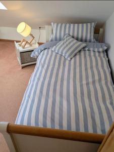 a bed with blue and white striped sheets and a lamp at Nicht Daheim und doch Zuhaus in Heiligenhafen +10 photos