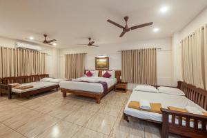 a bedroom with three beds and a ceiling fan at Shoolin Resorts in Manipal