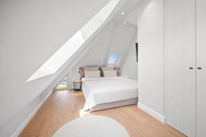 a white bedroom with a bed and a staircase at Traumloft Wenningstedt in Wenningstedt