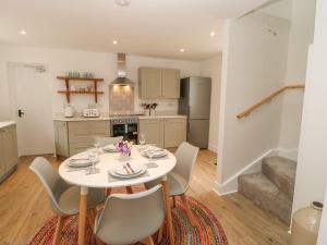 a kitchen and dining room with a white table and chairs at Dairy Cottage in Kirkby Stephen