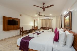 a bedroom with a large white bed with a couch at Shoolin Resorts in Manipal