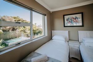 a bedroom with two beds and a large window at Shores Keep - Self Catering Home in Hermanus +71 photos