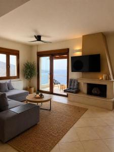 a living room with a couch and a tv at Vitamin Sea Luxury Villas in Agia Pelagia