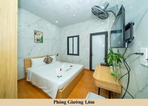 a bedroom with a large white bed and a tv at Green Homestay in Danang