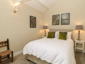 a bedroom with a large white bed with green pillows at Dairy Cottage in Kirkby Stephen