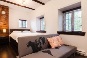 a bedroom with a bed and a couch and windows at Comfort & Getaway in Old Levis - Studio Urbain in Lévis