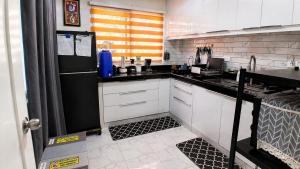 a kitchen with white cabinets and a black refrigerator at J&J Antipolo Place 2BR with Netflix & Karaoke in Antipolo +30 photos