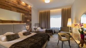 a hotel room with two beds and a chair at Sandra Spa Karpacz & Aquapark in Karpacz