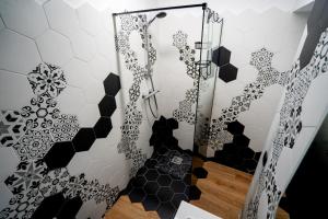a shower with black and white hexagonal tiles at Serafim's Suites Airport in Iaşi +42 photos