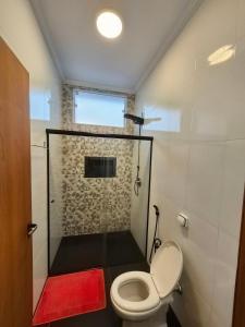 a bathroom with a shower with a toilet and a red rug at Recanto Luigi in Brotas +33 photos