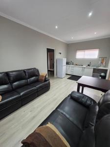 a living room with a black leather couch and a table at Munnik Rest in Polokwane
