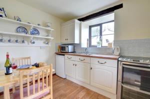 a kitchen with white cabinets and a wooden table at 1 Bed in Carmel oc-wai213 in Llanerchymedd