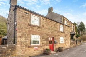 a brick house with a red door on a street at 1 Bed in Starkholmes oc-q30994 in Matlock Bank