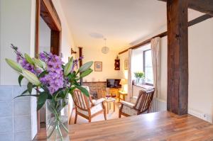 a vase of purple flowers on a table in a living room at 1 Bed in Llanerchymedd oc-wai212 in Llanerchymedd