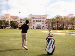 a man is playing golf in front of a house at Ona Mar Menor Golf & Spa in Torre-Pacheco