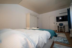 a bedroom with a white bed and a chair at Serafim's Suites Airport in Iaşi