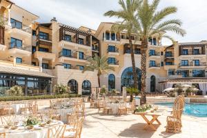 a hotel with tables and chairs in front of a pool at Ona Mar Menor Golf & Spa in Torre-Pacheco