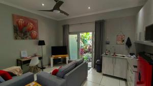 a living room with a couch and a kitchen at Utopia Guest House in Alberton