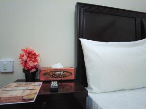 a bed with a clock on a table next to a pillow at Satti Palace Guest House in Rawalpindi