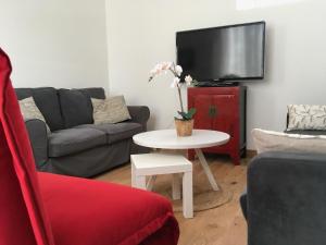 a living room with a couch and a table with a tv at Villa Myriam in Deauville