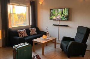a living room with a couch and a chair and a table at Villa IRIS 4, Himos in Jämsä